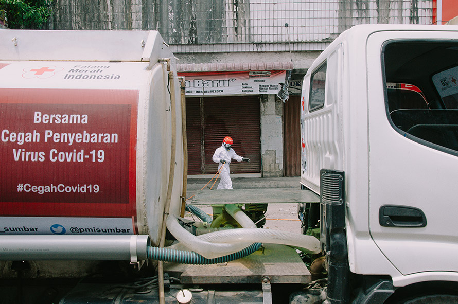 Kendaraan disenfeksi Palang Merah Indonesia dengan stiker himbauan terkait Covid 19, disampingnya terlihat Relawan PMI Kota Padang memegang selang disenfektan. Palang Merah Indonesia menjadi salah satu garda terdepan dalam upaya penanganan Virus Covid-19, dengan cara turun langsung ke tengah masyarakat. (givo alputra)