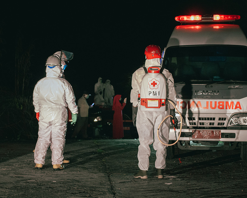 Relawan PMI memakai Alat Pelindung Diri (APD) lengkap berada di depan mobil Ambulance sebelum menguburkan jenazah pasien Covid19 di Kota Padang, Sumatra Barat, Minggu (19/04/2020). Palang Merah Indonesia menjadi salah satu garda terdepan dalam upaya penanganan Virus Covid-19, hingga turun ke dalam liang lahat untuk menguburkan korban postif. (givo alputra)