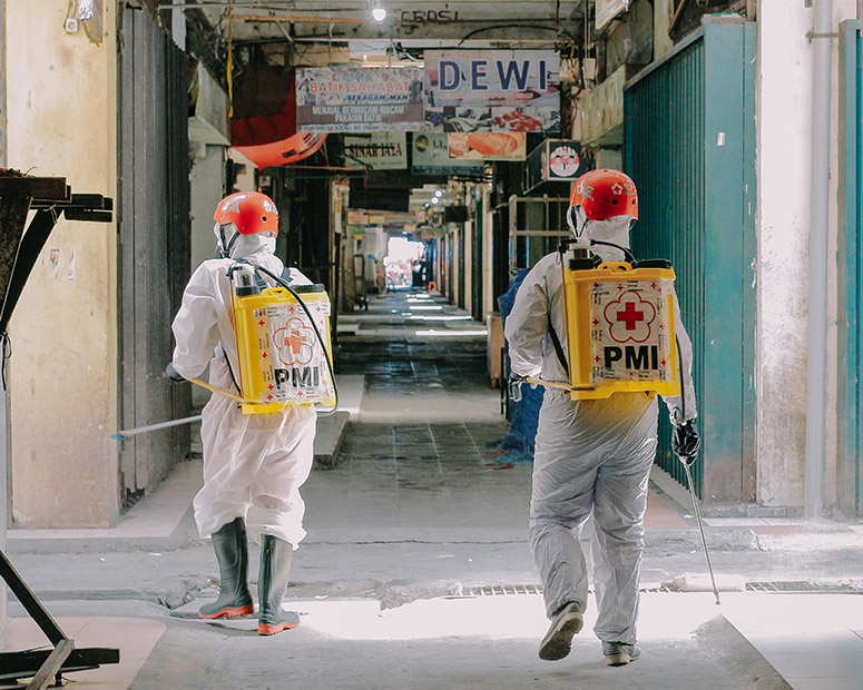Dua orang relawan Palang Merah Indonesia (PMI) berjalan dengan melewati ruko pedagang, saat melakukan penyemprotan cairan disenfektan di Pasar Raya Padang, Kota Padang, Sumatra Barat, Minggu (19/04/2020). Palang Merah Indonesia menjadi salah satu garda terdepan dalam upaya penanganan Virus Covid-19, dengan cara turun langsung ke tengah masyarakat. (givo alputra)